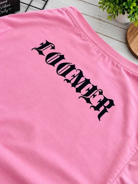 Close-up of Loomer lettering printed on a pink T-shirt